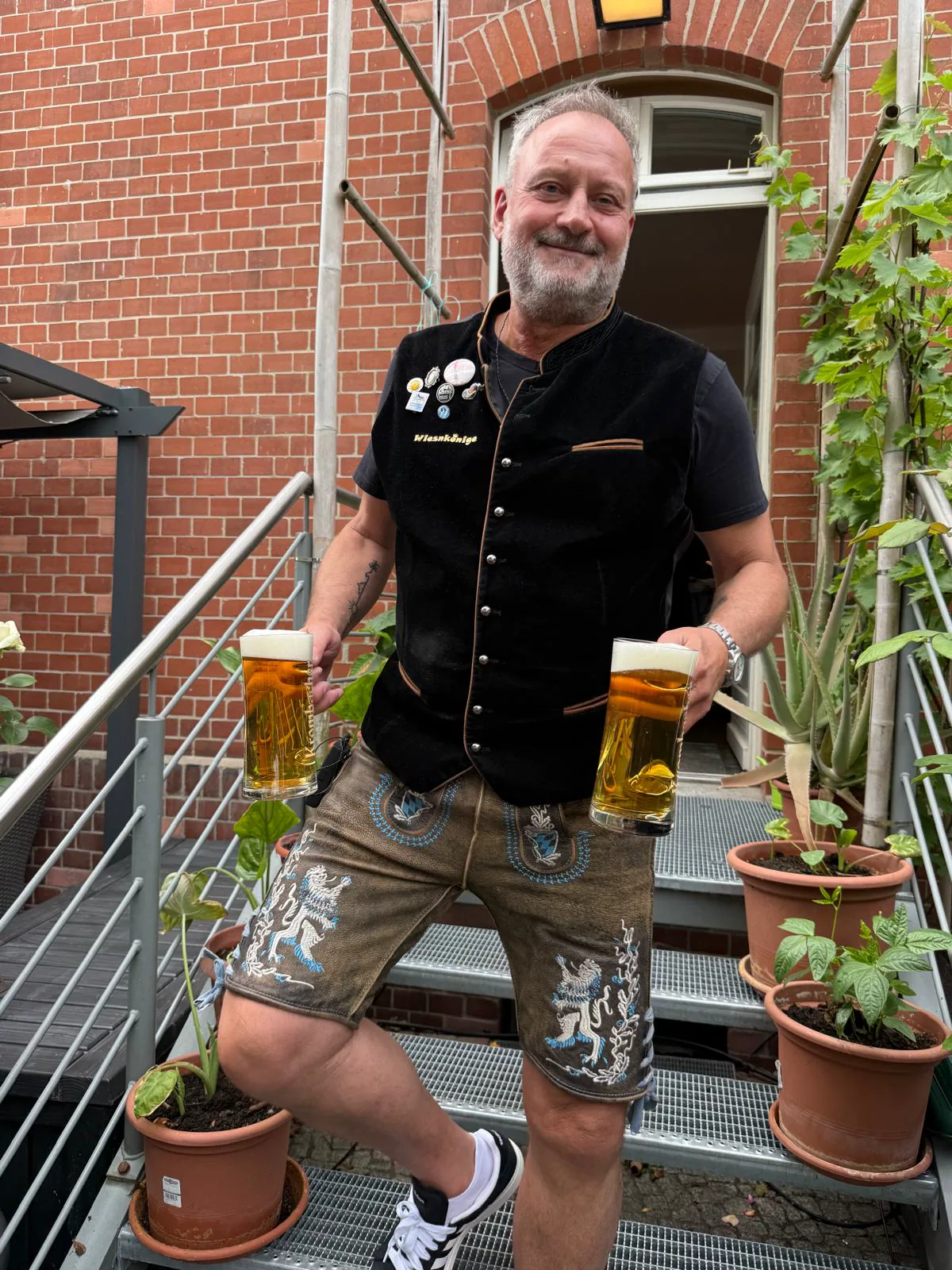 Musiker der Wiesnkönige in Tracht mit zwei Maßkrügen auf einer Treppe