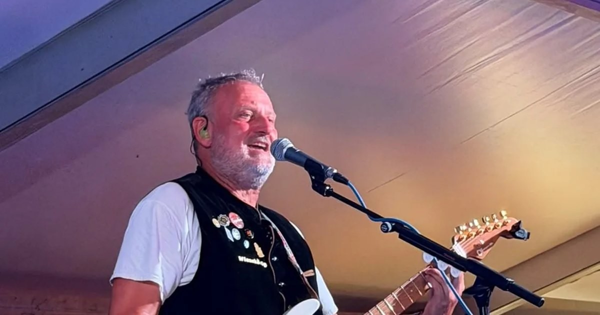 Michael Stern singt lachend ins Mikrofon, mit Gitarre unter einem Festzeltdach