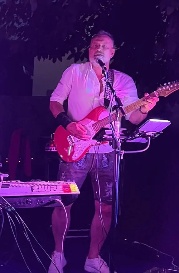 Auftritt mit roter E-Gitarre am Mikrofon im violetten Bühnenlicht