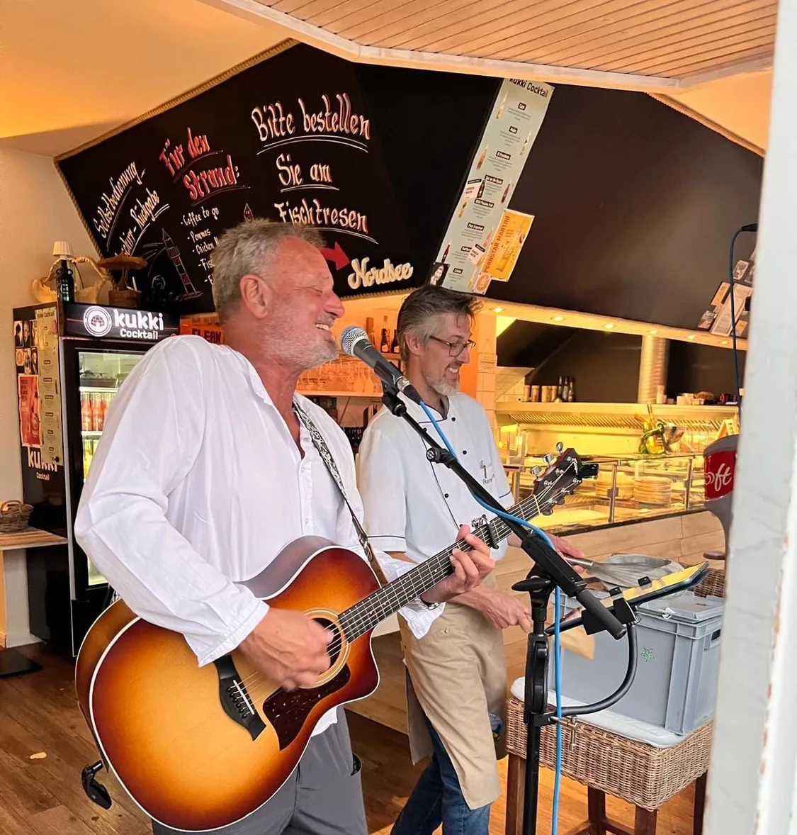 Michael Stern singt mit Akustikgitarre bei einem Auftritt in kleinem Rahmen